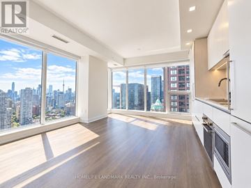 Toronto (North St. James Town) condo for rent - A spacious kitchen and living room with a view of the city skyline.