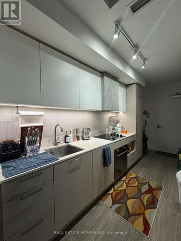Toronto (Niagara) condo for rent - A modern kitchen with white cabinets and a wooden floor.
