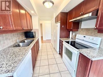 Toronto (Willowdale East) condo for rent - A kitchen with brown cabinets and white appliances.