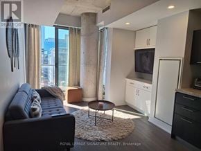 Toronto (Waterfront Communities) condo for rent - A living room with a black couch and a round table.