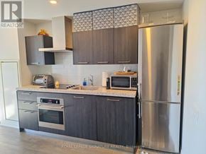 Toronto (Waterfront Communities) condo for rent - A modern kitchen with dark wood cabinets and stainless steel appliances.