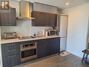 Toronto (Waterfront Communities) condo for rent - A kitchen with dark wood cabinets and stainless steel appliances.