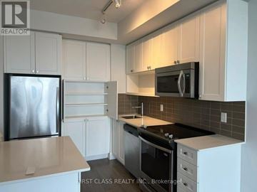 Toronto (Parkwoods-Donalda) condo for rent - A kitchen with white cabinets and a black fridge.