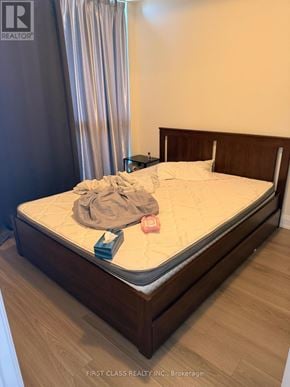 Toronto (Parkwoods-Donalda) condo for rent - A bed with a wooden headboard and footboard with a white mattress and a grey blanket on it.
