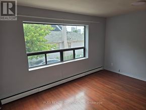 Toronto (Mimico) multi-family for rent - A room with a large window and wooden flooring.
