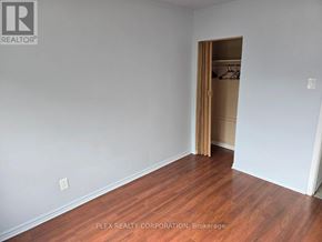 Toronto (Mimico) multi-family for rent - A room with a wooden floor and a white wall with a doorway leading to another room.