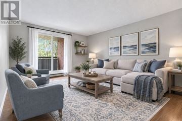 Chatham-Kent condo for rent - A living room with a grey sofa, a grey armchair, a wooden coffee table, and a rug.