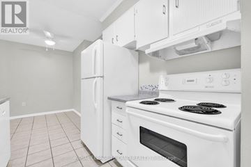Chatham-Kent condo for rent - A white kitchen with a stove top oven and a refrigerator.