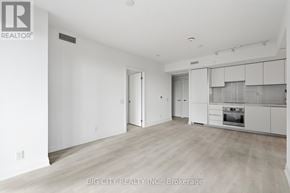 Toronto (Thorncliffe Park) condo for rent - A spacious, empty room with a kitchen area in the background.