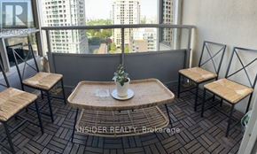 Toronto (Bayview Village) condo for rent - A balcony with a table and chairs overlooking a cityscape.