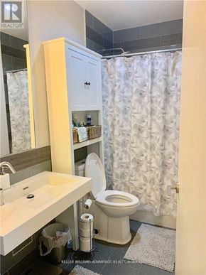 Toronto (Waterfront Communities) condo for rent - A bathroom with a white toilet, sink, and shower curtain.
