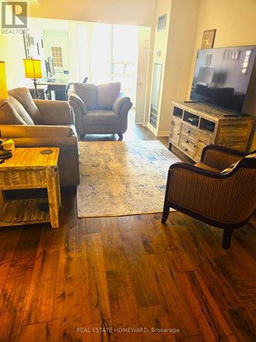 Toronto (University) condo for rent - A living room with a wooden floor and a television on a cabinet.