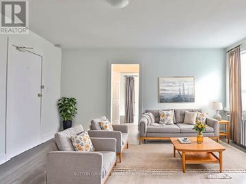Toronto (Little Portugal) multi-family for rent - A living room with a grey couch, a wooden coffee table, and a painting on the wall.
