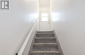 St. Catharines (Carlton/Bunting) apartment for rent - A staircase leading to a white door with a window.