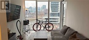 Toronto (Niagara) condo for rent - A living room with a couch and a bicycle in front of a window.