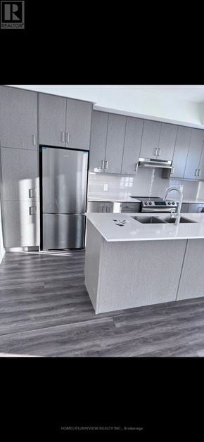Vaughan (Vaughan Corporate Centre) townhouse for rent - A modern kitchen with a refrigerator, sink, and cabinets.
