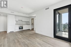 Toronto (Thorncliffe Park) condo for rent - A spacious, well-lit kitchen with white cabinetry and a view of the city through a large window.