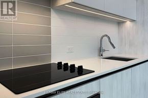Vaughan (Vaughan Corporate Centre) condo for rent - A modern kitchen with a black countertop and a stove top oven.