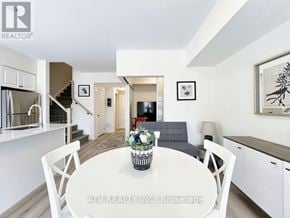 Richmond Hill (Mill Pond) townhouse for rent - A white dining table with chairs and a vase of flowers is in the center of a modern kitchen and living room.