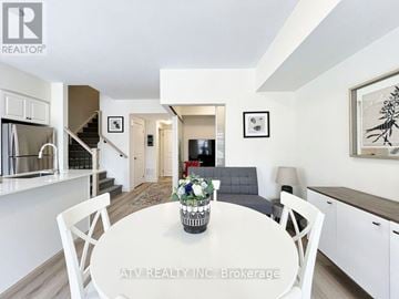 Richmond Hill (Mill Pond) townhouse for rent - A white dining table with chairs and a vase of flowers is in the center of a modern kitchen and living room.