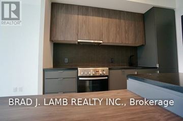 Toronto (Stonegate-Queensway) condo for rent - A modern kitchen with wooden cabinets and stainless steel appliances.