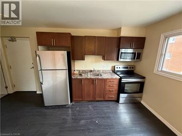 Kitchener apartment for rent - A kitchen with a refrigerator, microwave, oven, and sink.