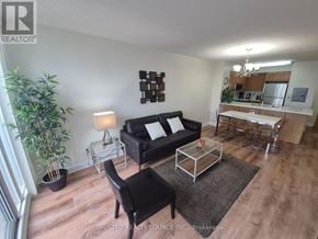 Toronto (Yonge-Eglinton) condo for rent - A living room with a black couch, a glass table, and a potted plant.