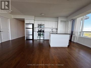 Toronto (Mimico) condo for rent - A kitchen with white cabinets and a refrigerator in a room with wooden floors.