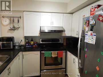 Toronto (Bathurst Manor) townhouse for rent - A kitchen with a refrigerator covered in magnets and a clock on the wall.