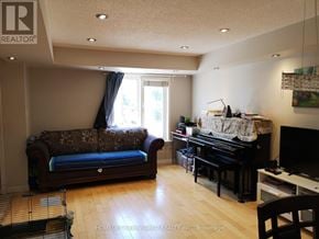 Toronto (Bathurst Manor) townhouse for rent - A living room with a couch, a piano, and a television.