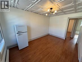 Kitchener apartment for rent - A room with wooden floors and a white refrigerator.