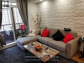 Vaughan (Maple) condo for rent - A living room with a grey couch, a coffee table with fruit on it, and a large window with curtains.