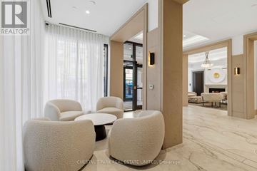 Toronto (Englemount-Lawrence) condo for rent - A living room with a white sofa and a white chair with a brown cushion.