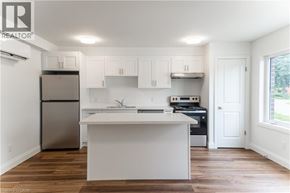 Kitchener apartment for rent - A white kitchen with wood floors and a refrigerator.