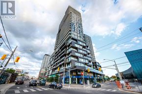 Toronto (Dovercourt-Wallace Emerson-Junction) condo for rent - A tall building with many windows is in the middle of a city street.