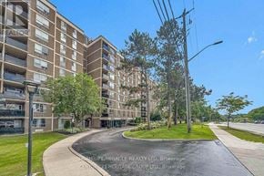 Toronto (Humber Summit) condo for rent - A residential building with a grassy area in front and a clear blue sky above.