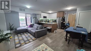 Toronto (Yorkdale-Glen Park) condo for rent - A living room with a grey sofa and a dining table.