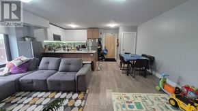 Toronto (Yorkdale-Glen Park) condo for rent - A living room with a grey sofa, a dining table with chairs, and a play area with toys.