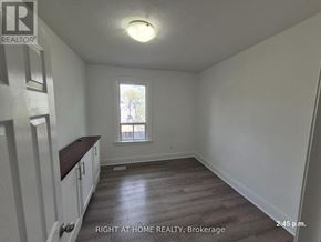 Oshawa (Central) apartment for rent - A room with wooden floors and white walls, with a window and a door on the left side.