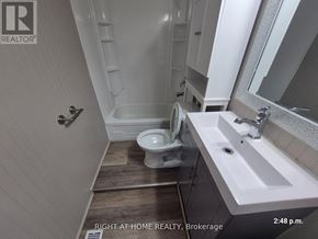 Oshawa (Central) apartment for rent - A bathroom with a toilet, sink, and mirror.