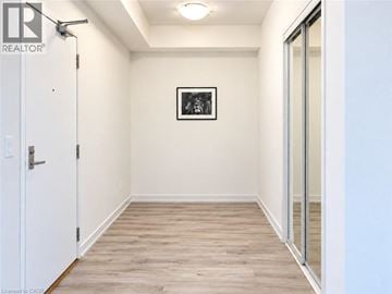 Waterloo condo for rent - A white door is on the left of a hallway with wood flooring and a picture on the wall.