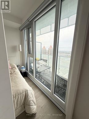 Mississauga (City Centre) condo for rent - A bedroom with a large window overlooking a cityscape.