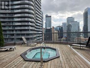 Toronto (Bay Street Corridor) condo for rent - A rooftop with a hot tub and chairs overlooking a city skyline.
