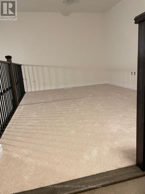 Wasaga Beach townhouse for rent - A room with a carpeted floor and a wooden railing.