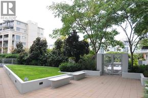 Vancouver apartment for rent - A green space with benches and a fence in front of a building.
