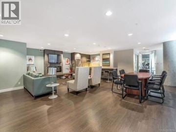 Vancouver apartment for rent - A living room with a grey sofa, a white armchair, a wooden table and a television.