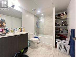 Toronto (Waterfront Communities) condo for rent - A small, white bathroom with a toilet, sink, and a large mirror.