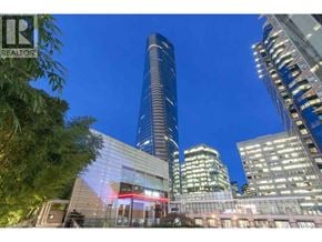 Vancouver apartment for rent - A tall building with a glass facade stands in front of other buildings at night.