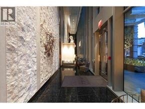 Vancouver apartment for rent - A hallway with a marble floor and a stone wall on the left side.