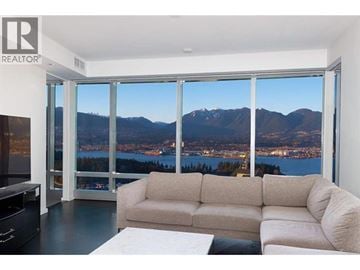 Vancouver apartment for rent - A living room with a couch and a television in front of a window with a view of a city and mountains.